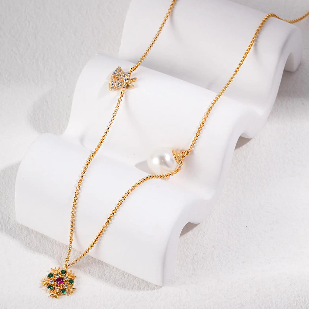 A gold necklace elegantly displayed on a white stand, featuring a sunburst pendant with multicolored gemstones at the center and a large, solitary pearl. The chain is simple, ensuring that the focus remains on the intricate design of the pendant and the pearl, signifying a blend of modern luxury and classic beauty.